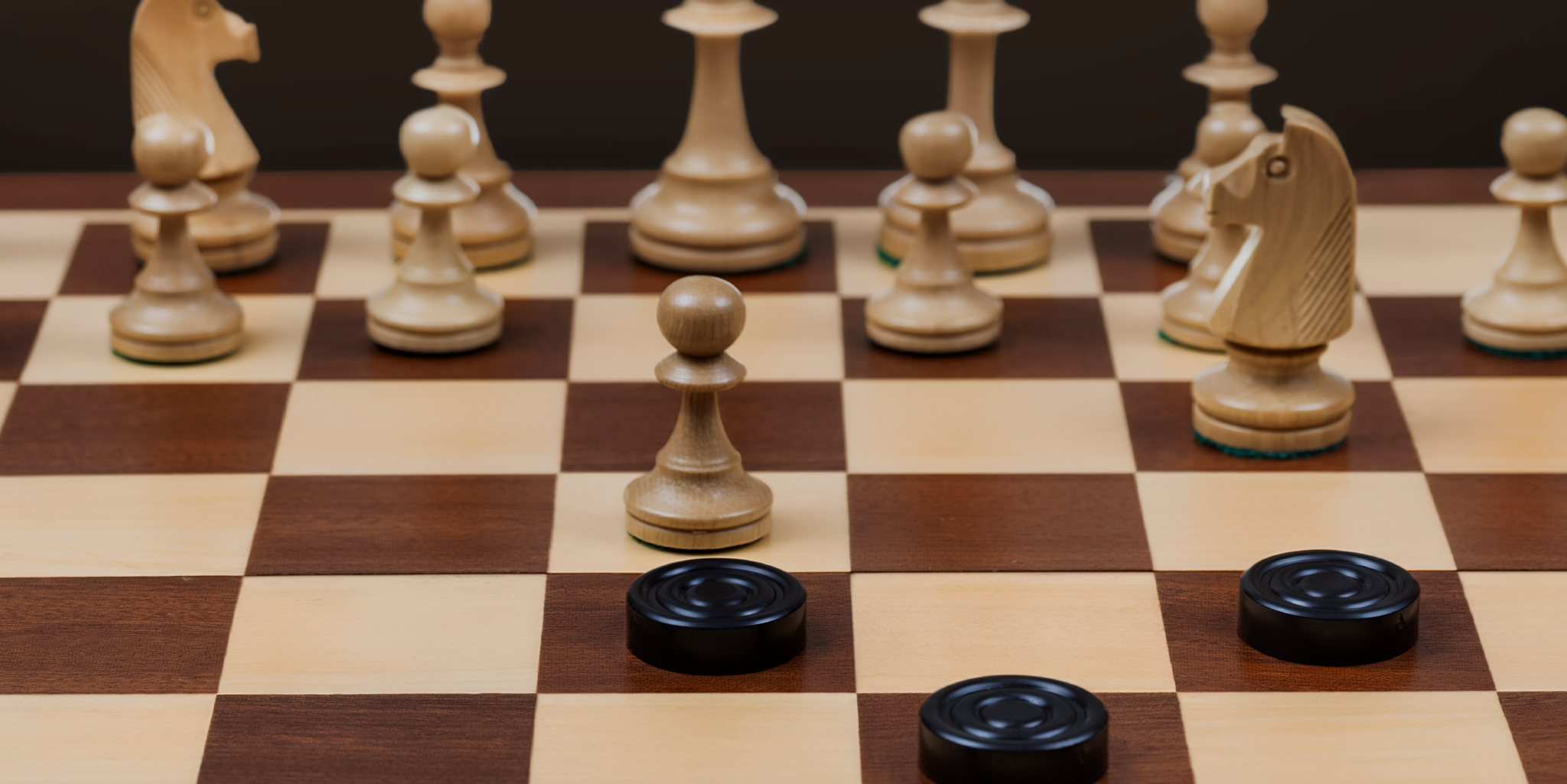 A chess board with chess pieces played against checkers pieces.