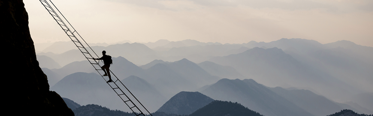 A person climbing a mountain on a rope ladder